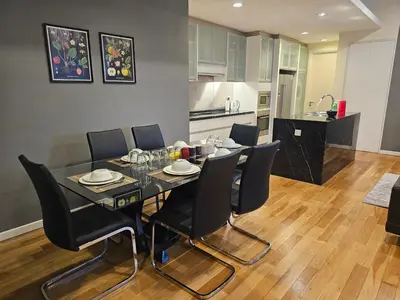 a dining room table with black chairs and a kitchen at Cosy Apartment at St Mary KL City Centre in Kuala Lumpur
