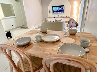 a wooden table with plates and wine glasses on it at VintageHome Lalaport Casa Mutiara Bukit Bintang by Scape Stay in Kuala Lumpur