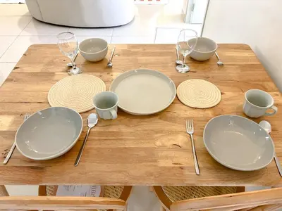 a wooden table with plates and utensils on it at VintageHome Lalaport Casa Mutiara Bukit Bintang by Scape Stay in Kuala Lumpur