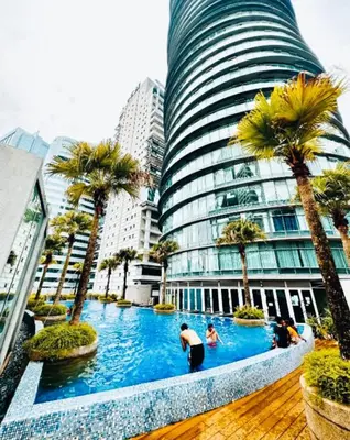a hotel swimming pool with palm trees and a tall building at Vortex Suites KLCC 10 Pax -3 Bedroom Apartment in Kuala Lumpur