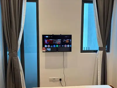 a room with a tv and two windows with curtains at Luxe Suites Home KLCC in Kuala Lumpur