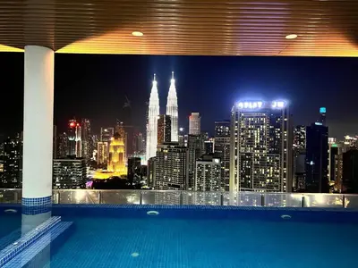 a view of a city at night from a swimming pool at The Luxe Suites Infinitum KLCC in Kuala Lumpur