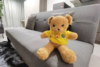 a teddy bear wearing a yellow shirt sitting on a couch at Modern Comfy Studio Permaisuri 2 Carpark WIFI in Kuala Lumpur