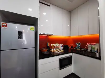 a kitchen with white cabinets and an orange wall at Arcoris Mont Kiara 15# 163 Sunway Mall # 1 Mont Kiara in Kuala Lumpur