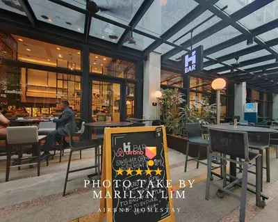 a restaurant with tables and chairs and a sign in front of it at Arcoris Mont Kiara 18# Sunway 163 Mall# 1 Mont Kiara # 2 BR with Balcony 2-4 Pax in Kuala Lumpur