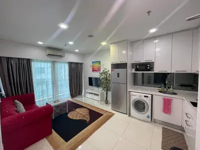 a living room with a red couch and a kitchen at Mercu summer suites By Premium Charter in Kuala Lumpur