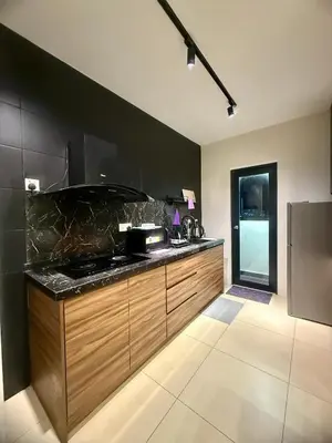 a kitchen with wooden cabinets and a black wall at REIZZ RESIDENCE BY BERJAYA in Kuala Lumpur