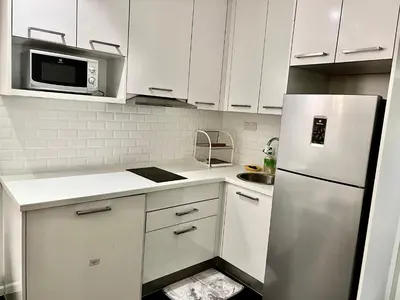 a kitchen with white cabinets and a stainless steel refrigerator at Summer Suites KLCC By Victorians in Kuala Lumpur