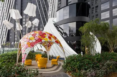 a garden with a pavilion with a umbrella and yellow chairs at VALENTINA SUITES @ ARTE MONT KIARA in Kuala Lumpur