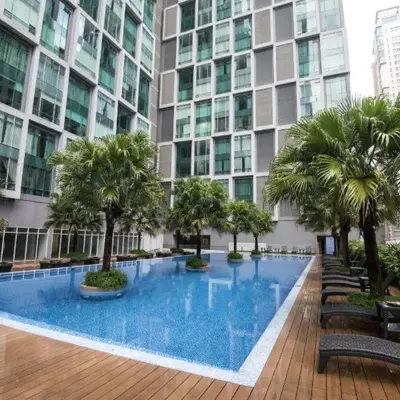a large building with a large swimming pool with palm trees at Soho Suites KLCC in Kuala Lumpur