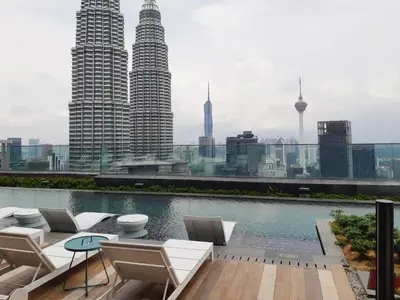 a rooftop patio with chairs and a pool with a city skyline at KLCC Star Suites by BBA in Kuala Lumpur