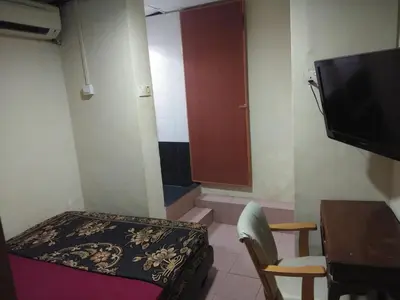 a small room with a bed and a table and a tv at KL CITY LODGE in Kuala Lumpur