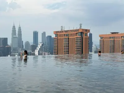 a group of people swimming in the infinity pool of a city at Smart Home at Lucentia Residence BBCC Lalaport in Kuala Lumpur