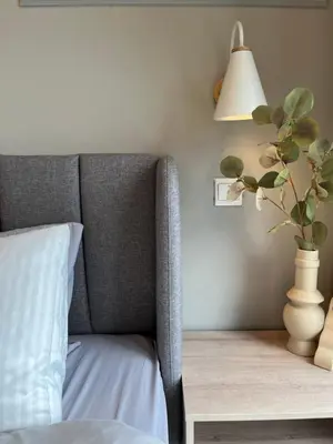 a bedroom with a gray chair and a table with a lamp at NJ Homestay AT TRION, KL in Kuala Lumpur