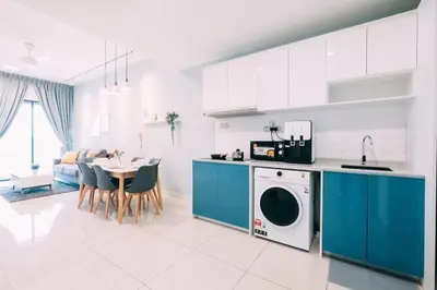 a kitchen with blue cabinets and a table with a washing machine at Continew Residensi by Feel Home in Kuala Lumpur