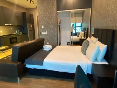 a bedroom with a large bed and a living room at Ceylonz Suites By MyStay in Kuala Lumpur