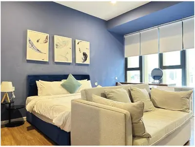 a blue bedroom with a bed and a couch at Ceylonz Suites By MyStay in Kuala Lumpur