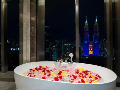 a bath tub filled with flowers in front of a window at Imperial Luxury Suites KLCC by Moonway in Kuala Lumpur