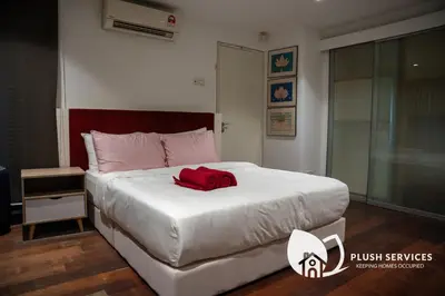 a bedroom with a bed with a red pillow on it at Damansara Heights by Plush in Kuala Lumpur