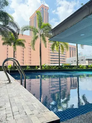 a swimming pool with palm trees and a building at Cozy home in city center with free parking -1B in Kuala Lumpur