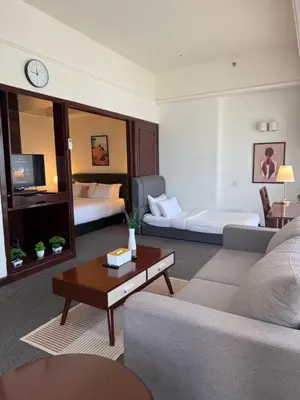 a living room with a couch and a room with two beds at Luxhouz Suites at Times Square Kuala Lumpur in Kuala Lumpur