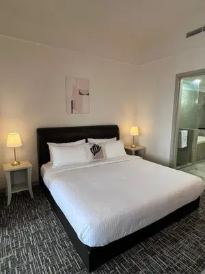 a bedroom with a large white bed with two lamps at Luxhouz Suites at Times Square Kuala Lumpur in Kuala Lumpur