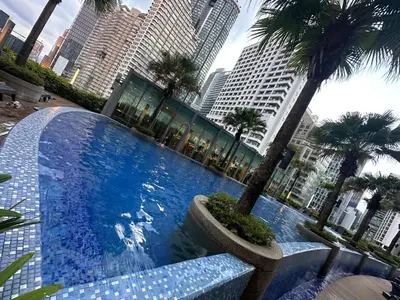 a large swimming pool with palm trees and buildings at Vortex Suites KLCC by ZARA in Kuala Lumpur