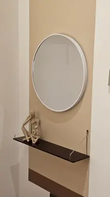 a round mirror on a shelf in a bathroom at Neu Suites in Kuala Lumpur