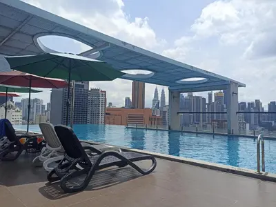 a swimming pool with chairs and umbrellas on a building at D'Majestic Place, 1 King or 2 Super Single beds in Kuala Lumpur