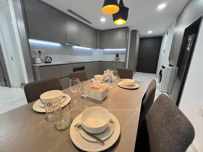 a dining room with a table with plates and glasses at Eaton Residence KLCC By HM Costa Doro in Kuala Lumpur