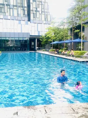 a man and a child swimming in a swimming pool at Eastern Suites Star KLcc in Kuala Lumpur