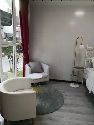 a living room with a white chair and a bed at Titiwangsa Cabin Retreats by uBook in Kuala Lumpur