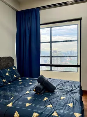 a bedroom with a blue bed with a large window at Arte Mont Kiara By ANQ Suites in Kuala Lumpur