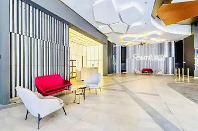 a lobby with a red chair and white chairs at TRX Continew Residence by Nia in Kuala Lumpur