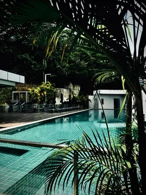 a swimming pool with a palm tree in the foreground at Damas Hotel,Suites and Residence at Plaza Damas 3 by Over The Moon in Kuala Lumpur