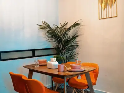 a wooden table with orange chairs and a plant at Scarletz Suites KLCC by Luxe Suites in Kuala Lumpur