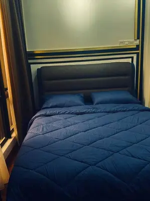a bed with a blue comforter in a bedroom at Blue cozy duplex house in Kuala Lumpur