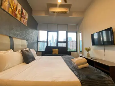 a bedroom with a large white bed with a television at Staybliss At Ceylonz Suites in Kuala Lumpur