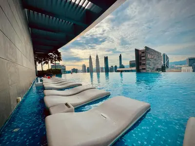 a row of chaise lounges in a pool with a city skyline at Eaton Service Apartment at KLCC in Kuala Lumpur