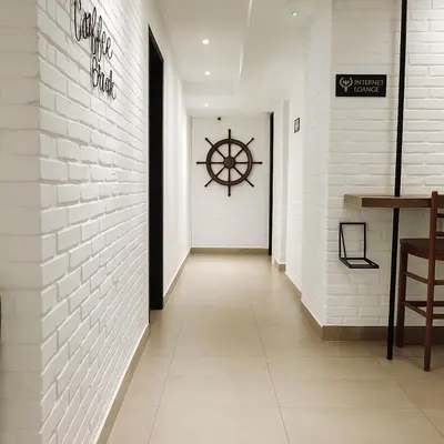 a hallway with a white brick wall and a wheel on the wall at Hotel 1915 Chinatown Kuala Lumpur in Kuala Lumpur