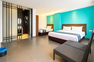 a hotel room with two beds and a chair at Hotel 1915 Chinatown Kuala Lumpur in Kuala Lumpur