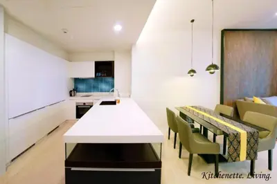 a kitchen and dining room with a white table and chairs at Tropicana The Residences by uBook in Kuala Lumpur