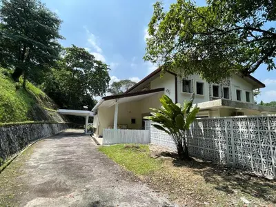 a white house with a fence next to a dirt road at Bukit Tunku Grande Villa by uBook in Kuala Lumpur
