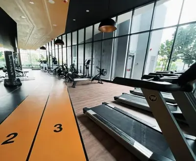 a gym with rows of treadmills in a room with windows at Neu suites cozy 2 bedrooms family house in Kuala Lumpur
