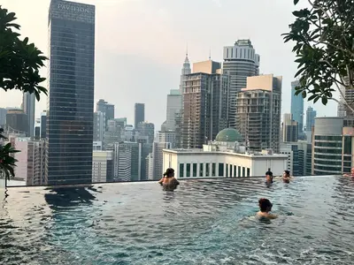 a group of people swimming in a infinity pool with a city skyline at Axon Residence Suites KL in Kuala Lumpur