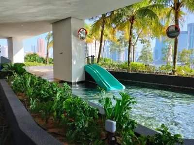 a water slide in a pool with palm trees at KL Sanctuary Style Comforts, Pool, Gym, Near MRT! in Kuala Lumpur