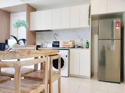a kitchen with white cabinets and a table and a refrigerator at Charming Haven in Kuala Lumpur 100Mb TRX Mall in Kuala Lumpur