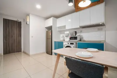 a kitchen with a wooden table and blue and white cabinets at Sleek 3BR Suites Near TRX By Rumabnb in Kuala Lumpur