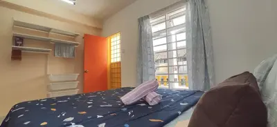 a bedroom with a bed with blue sheets and a window at Hostel Room with Private Bathroom in Kuala Lumpur