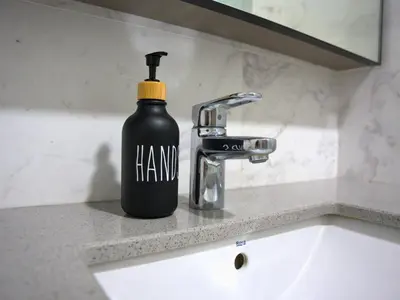 a black bottle of hand soap sitting on a bathroom sink at Eaton Residence Yemala in Kuala Lumpur